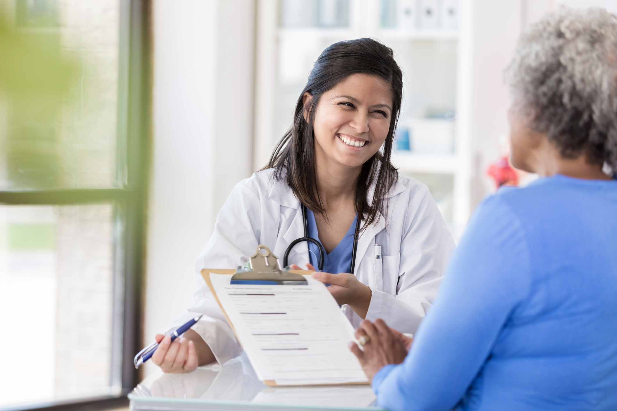 Female doctor laughs with patient during paperwork